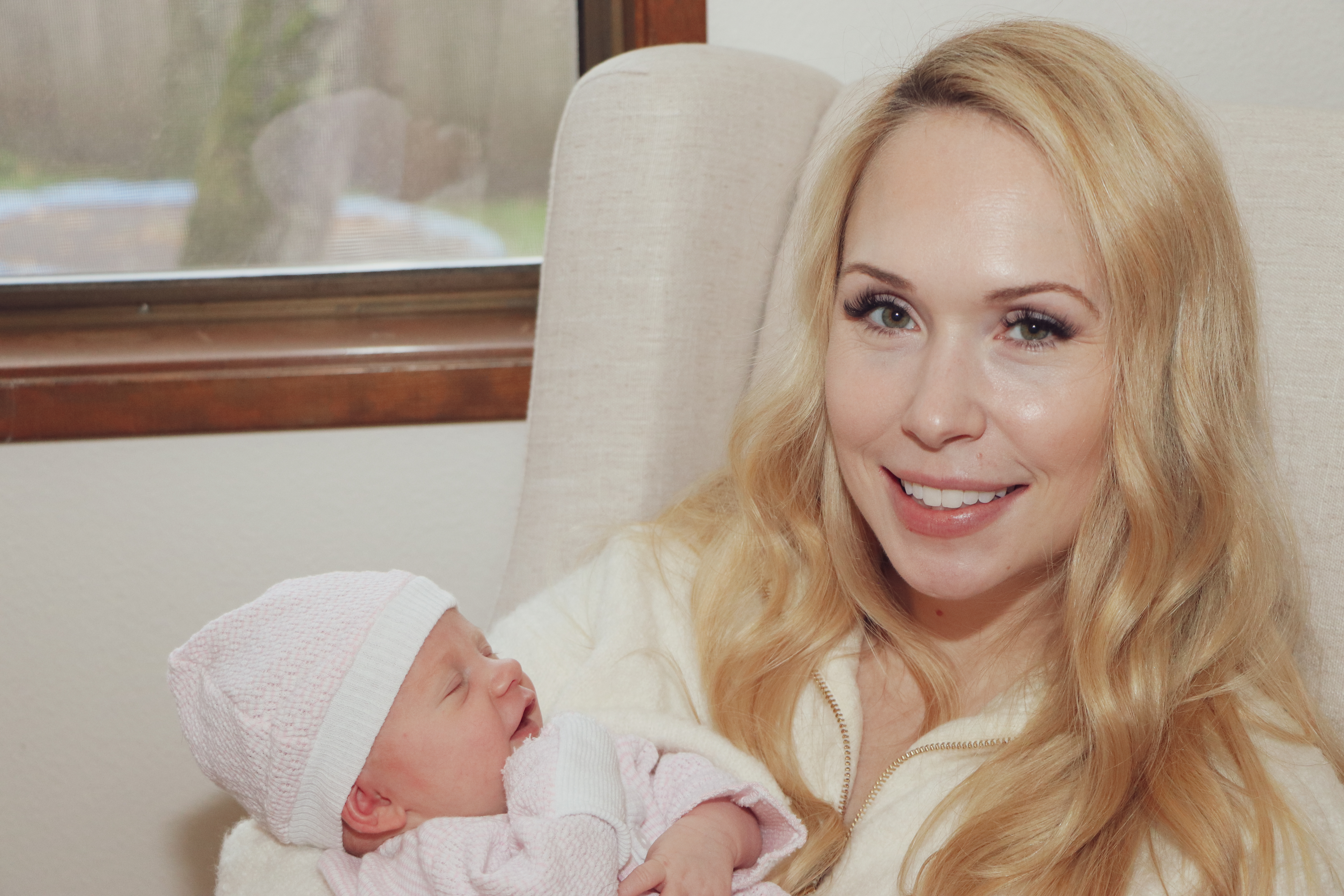young mom holding newborn by window