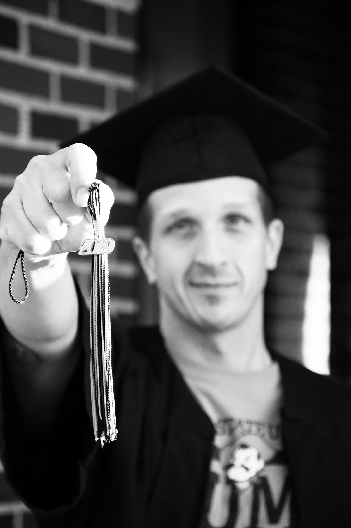a young man holding up a graduation tassle